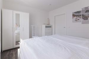 a white bedroom with a white bed and a dresser at Born - Wieck DAT SCHWEDENHUS EG-Whg. WI-4.1 in Wieck