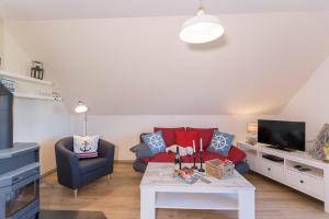 a living room with a red couch and a table at Born - Wieck DAT SCHWEDENHUS OG-Whg. WI-4.2 in Wieck