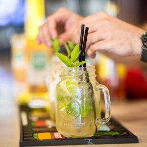 a person holding a mason jar with a green drink at Logis Hôtel Le Glacier in Orange