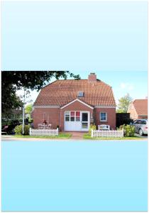 a red brick house with a white fence at Ferienwohnung Haus Schwalbennest OG in Ditzum