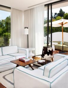 Una sala de estar con muebles blancos y grandes ventanales. en Condesa df, Mexico City, a Member of Design Hotels, en Ciudad de México