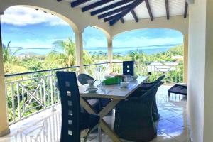 a table and chairs on the balcony of a house at Spacieuse villa à Deshaies avec piscine privée in Deshaies