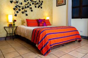 a bedroom with a bed with a colorful striped blanket at Hotel Las Marias in Antigua Guatemala