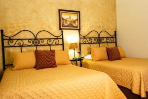 two beds in a hotel room with yellow sheets at Hotel Las Marias in Antigua Guatemala