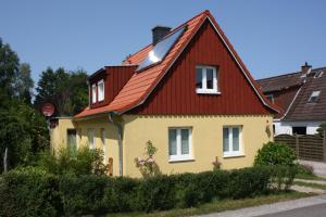 żółty i czerwony dom z czerwonym dachem w obiekcie Öko-Ferienwohnung-Kiel Lachmöwe w Kilonii