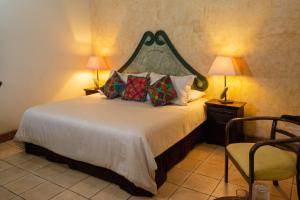 a bedroom with a bed with two lamps and a chair at Hotel Las Marias in Antigua Guatemala