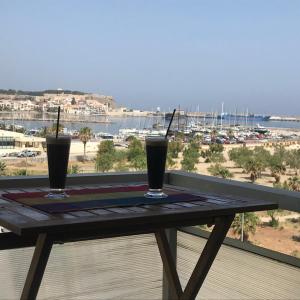 two drinks sitting on a wooden table on a balcony at Apartment on the Beach with View in Rethymno Town