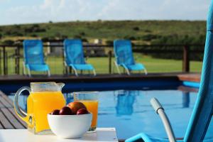 una mesa con un bol de fruta y zumo junto a una piscina en Cabañas Colinas Serranas en Tandil