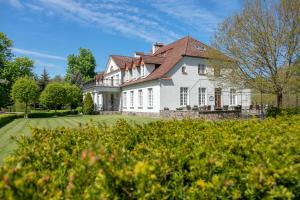 une grande maison blanche avec un toit rouge dans l'établissement Dwór w Bychowie, à Bychowo