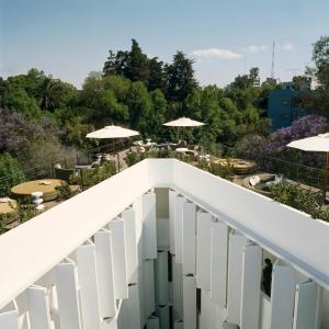 a balcony with tables and umbrellas in a garden at Condesa df, Mexico City, a Member of Design Hotels in Mexico City