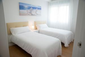 dwa łóżka w pokoju z białą pościelą w obiekcie L2 Apartamento O Grove Centro 2 hab con Aire Ac Parking w mieście O Grove