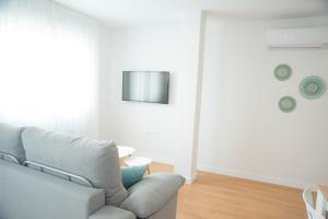 sala de estar con sofá y TV en la pared en L3 Loft O Grove Centro aire acondicionado parking, en O Grove