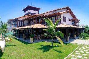 a house with a palm tree in front of it at Oceanica 1000 Beachfront Suites in Saquarema