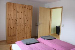 1 Schlafzimmer mit 2 Betten mit rosa Bettwäsche und einem Spiegel in der Unterkunft Winzerhof Senn in Vogtsburg