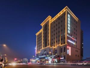 um grande edifício com luzes acesas à noite em Kyriad Hotel Dongguan Dalingshan South Road em Dongguan