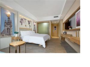 um quarto com uma grande cama branca e uma mesa em Kyriad Hotel Dongguan Dalingshan South Road em Dongguan