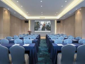 a conference room with blue tables and chairs and a screen at Kyriad Mavelous Hotel Shantou Gurao in Shantou