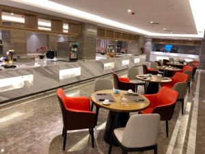 a restaurant with tables and chairs and a bar at Kyriad Mavelous Hotel Shantou Gurao in Shantou +6 photos