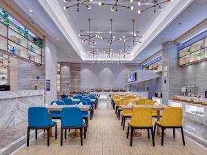 LeiyangにあるKyriad Hotel Leiyang West Lake Amusement Parkの青と黄色の椅子とテーブルが備わるレストラン