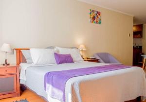 1 dormitorio con 1 cama grande con manta morada en UH ApartHotel Lastarria, en Santiago
