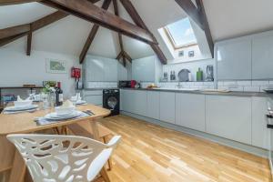 a kitchen with white cabinets and a table and chairs at The Shires in St. Agnes 