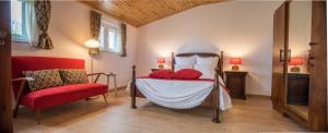 Un dormitorio con una cama con almohadas rojas y una silla en Casa dos Castanheiros, en Vila Verde