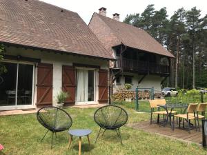 un patio con sillas y mesas frente a una casa en logement avec accès piscine, en Chaumont-sur-Tharonne