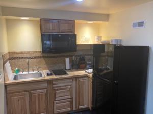 uma cozinha com um frigorífico preto e um lavatório em Yellowstone Riverside Cottages em Gardiner