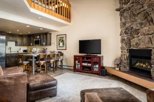 een woonkamer met een tv en een open haard bij Ptarmigan House in Steamboat Springs