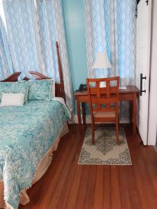 a bedroom with a bed and a chair and a desk at The Great House Inn in Belize City