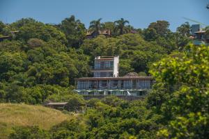 une maison au sommet d'une colline avec des arbres dans l'établissement Pousada Pedra Grande, à Praia do Rosa