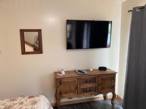 a bedroom with a wooden dresser and a television on the wall at Yellowstone Riverside Cottages in Gardiner
