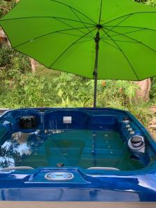 - un parasol vert assis à côté d'une baignoire bleue dans l'établissement Ô TI JACKO, au Gosier