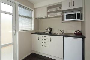 a kitchen with white cabinets and white appliances at 315 Motel Riccarton in Christchurch