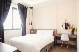 a bedroom with a bed and a chair and a window at Pontus Hotel in Da Lat