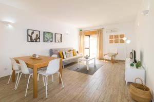 uma sala de estar com uma mesa e cadeiras e um sofá em Sunny Home Oura By ALzira em Albufeira