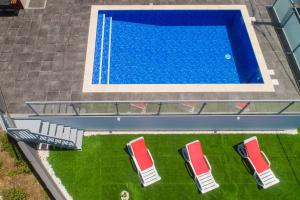 an overhead view of a swimming pool with red chairs at Roraima House - Private Pool & Garden in Calheta