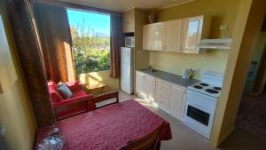 a small kitchen with a red couch and a window at Blakes Manor Self Contained Heritage Accommodation in Deloraine