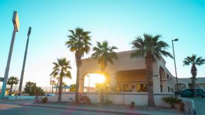 un bâtiment avec des palmiers en face du coucher du soleil dans l'établissement Rio Del Sol Inn Needles, à Needles