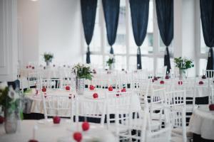 Hotel Park Sfantu Gheorghe في سفنتو جيورجي: غرفة مليئة بالطاولات البيضاء والكراسي عليها الورود