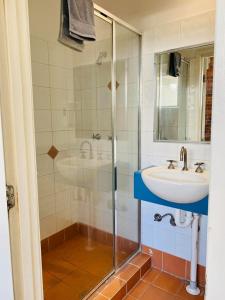 y baño con ducha acristalada y lavamanos. en Summer House Backpackers Brisbane en Brisbane