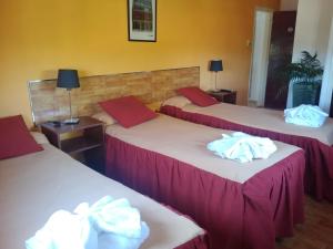 Tres camas en una habitación de hotel con toallas. en Hotel Aoma Villa Carlos Paz en Villa Carlos Paz