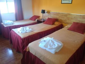 
a hotel room with two beds and two tables at Hotel Aoma Villa Carlos Paz in Villa Carlos Paz
