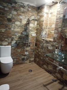 y baño con paredes de piedra, ducha y aseo. en Suite Love Jacuzzi (Casas Toya), en Uceda