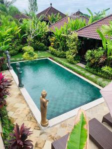 a pool with a statue in the middle of a yard at Villa D'Uma in Ubud