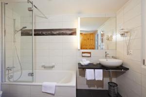 a bathroom with a tub and a sink and a shower at Hotel Welschen in Zermatt