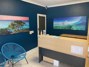 a room with a desk and a blue wall at Blue Pelican Motel in Tweed Heads