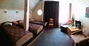 um quarto de hotel com duas camas e um sofá em Kalna Ligzda em Smiltene