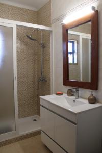 uma casa de banho com um lavatório e um chuveiro com um espelho. em Abrigo das Nortadas em Vila do Bispo