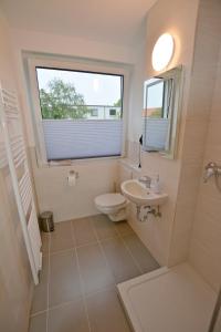 ein Bad mit einem WC, einem Waschbecken und einem Fenster in der Unterkunft Appartement Wildkamp in Salzgitter